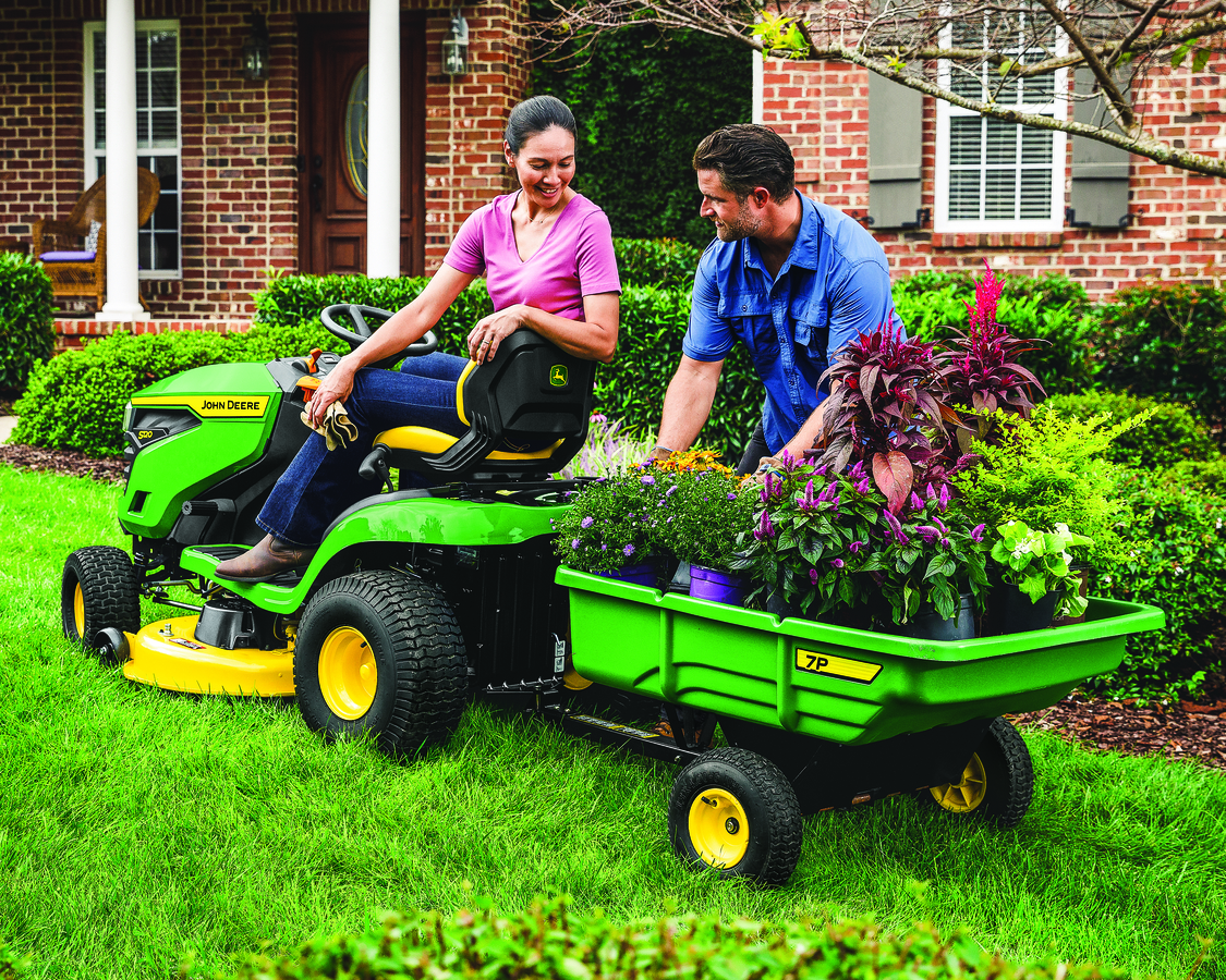 a couple is sitting on the john deere lawn tractor with attachment